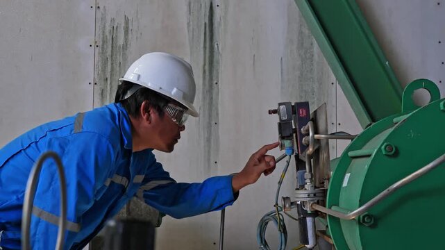 Senior process engineer inspecting an analog pressure gauge installed on a chemical process pipeline in a modern industrial plant, ensuring safe operation, equipment reliability, and process efficienc