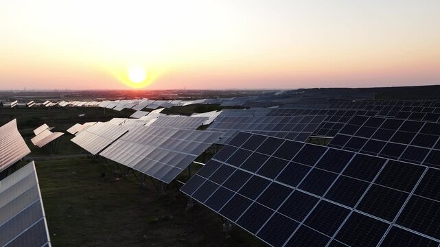 Large-scale photovoltaic power station array landscape during sunset with solar panels aligned across open fields