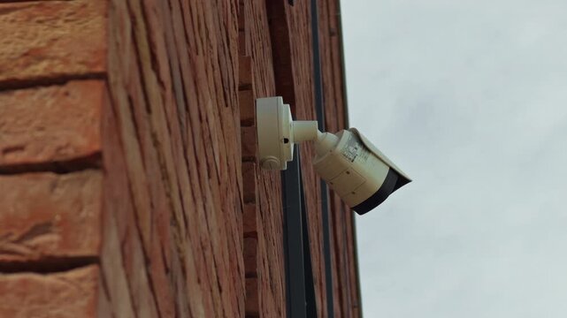 Security camera mounted on brick wall overlooking open sky for property monitoring