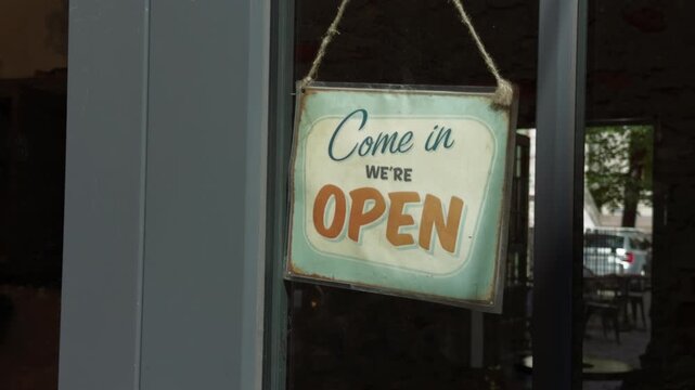 Hanging open sign on glass storefront door with rustic vintage welcome display