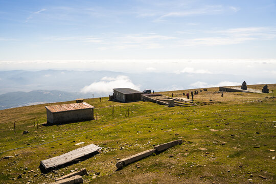 View of Botev Peak in the Balkan Mountains, featuring rustic mountain huts, stone steps, and hikers on a grassy plateau in Balkan Mountains, Lovech, Bulgaria.