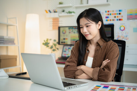 Female creative professional planning a visual design project with color samples, papers, and digital tools on her desk.