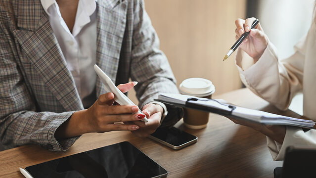 Two businesswomen wearing formal suit analyzing financial documents in the office