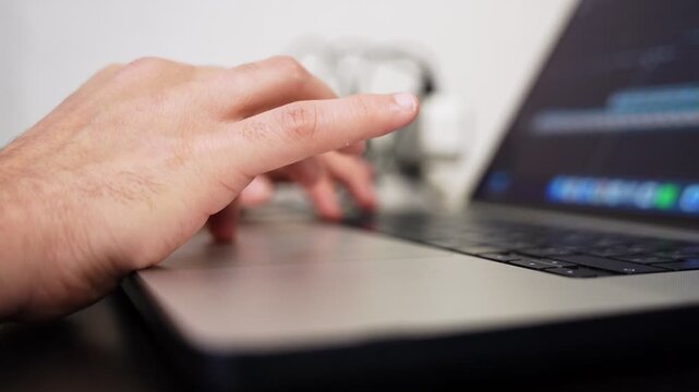 Close up of a person's hand using a laptop computer touchpad for navigation and typing.