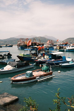 View of fishing boats moored in the harbor with mountains in the background under a clear sky in Hong Kong, Hong Kong.