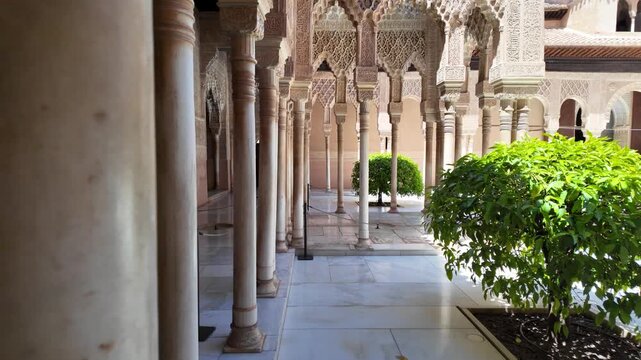 Slow motion reveal from behind a marble column showcasing the courtyard and ornate Islamic architecture of the Nasrid Palaces in the Alhambra, Granada, Spain