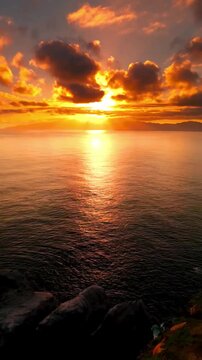 Stunning golden sunset over the ocean with a rocky cliff silhouette