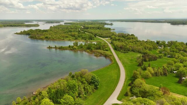 Drone aerial footage of Long Sault Parkway in Ontario, Canada, featuring a scenic roadway crossing a chain of islands surrounded by vibrant turquoise waters in the St. Lawrence River.