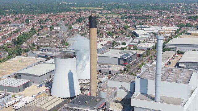 Aerial view of a multi fuel power station. Steam rises from a tall chimney and large cooling towers.