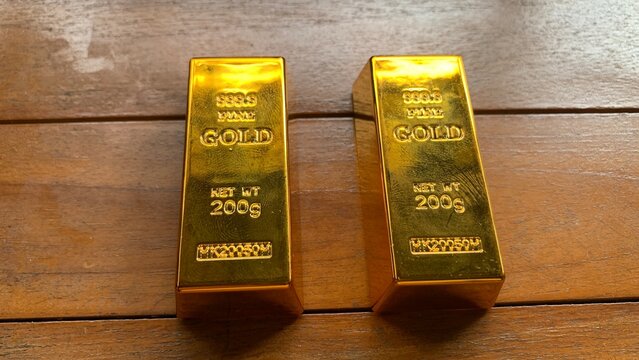 Two gold bars placed parallel on wooden surface, purpose for marketing or background