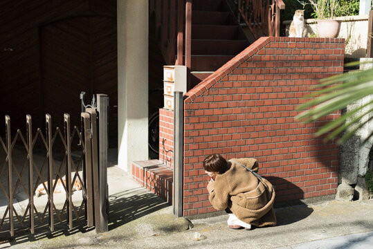 路地裏で猫と触れ合う女性の後ろ姿