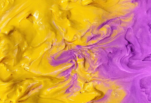 Yellow and purple oil paint mixed together. Abstract swirl texture and pattern of artistic thick acrylic color. Creative background for design art project and wallpaper surface.