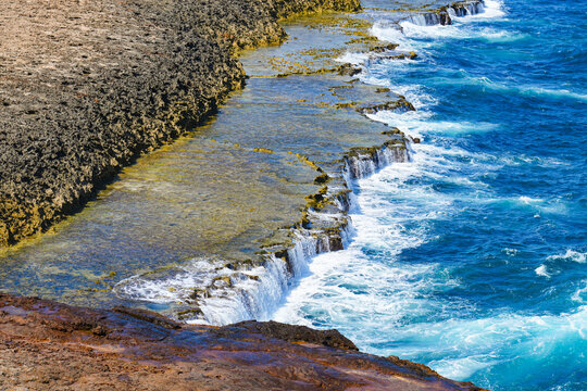Rugged limestone cliffs and crashing waves of the Caribbean Sea at Sero Colorado ocean plateau in Aruba