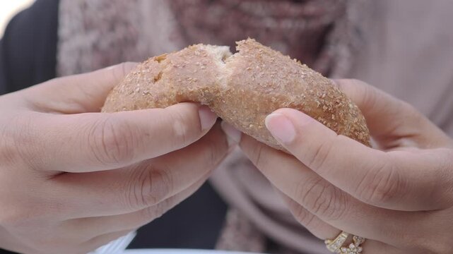 A person breaking a warm piece of bread in a cafe setting