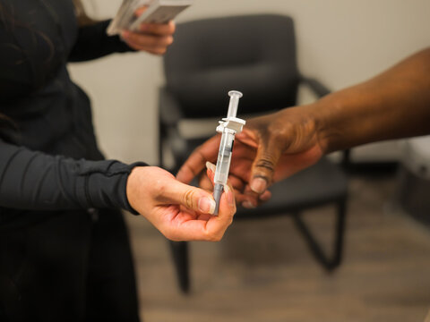 Clinic Staff Transferring Prefilled Syringe to Nurse for Procedure
