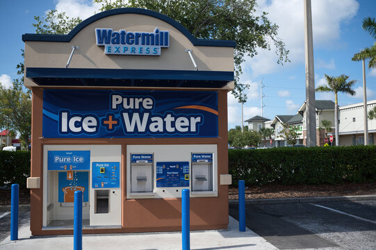 Small Watermill Express kiosk offering pure bagged ice and filtered water in a suburban parking lot. Editorial Use Only June 20, 2026 St. Petersburg, FL USA. Under blue skies, surrounded by trees and 