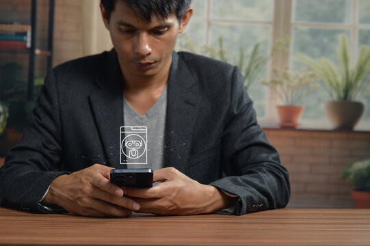Young Man Using Smartphone at Table in Bright Indoor Space with Large Windows