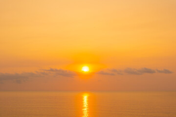 Obraz premium nature sky breathtaking golden sunset over a calm ocean, with the entire sky and water bathed in brilliant shades of yellow and orange. Streaky clouds enhance the dramatic display 