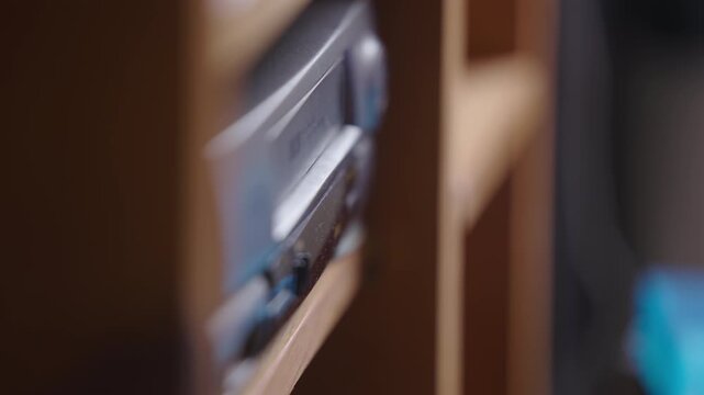 VHS cassette ejects from player revealing broken tape, close up, indoor setting