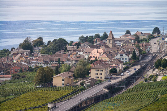 View of Les vignes de Lavaux terraced vineyards surrounding the town of Bourg-en-Lavaux with its church tower, railway tracks, and Lake Geneva, Bourg-en-Lavaux, Vaud, Switzerland.