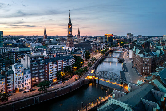 Aerial view of the historic Speicherstadt district in Hamburg, featuring iconic brick warehouses, canals, bridges, and the city skyline at dusk, Hamburg, Hamburg, Germany.