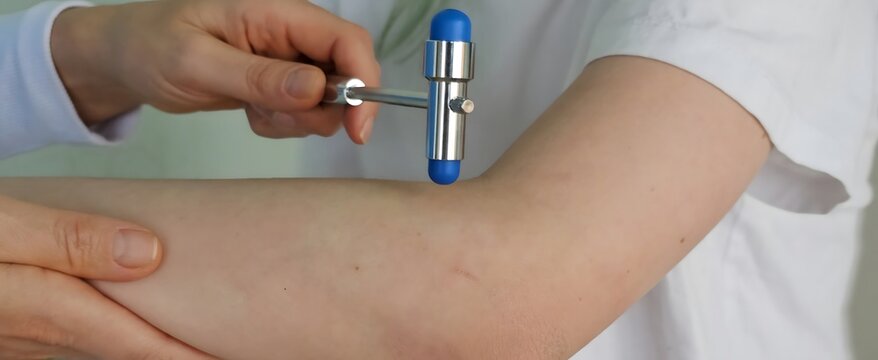Doctor hand elbow hammer teenager. Neurology. Checking a child hand with a neurological needle hammer in a neurological
