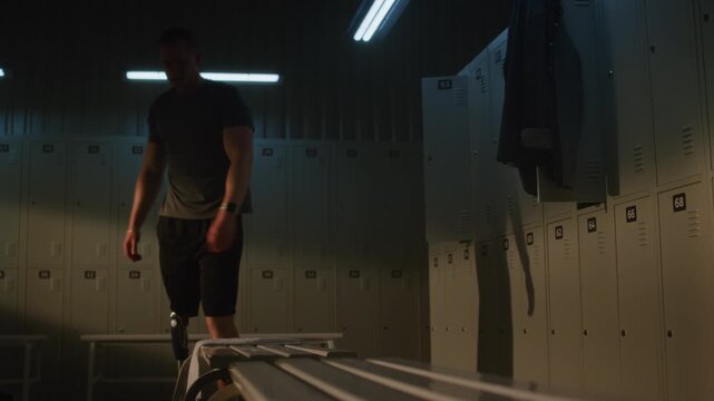 Determined Young Man with Prosthetic Limb Prepares for Workout by Tying Shoelaces on White Sneaker in Sports Club Dressing Room. Concept of Resilience, Diversity, Real People, Daily Routine. Handheld.