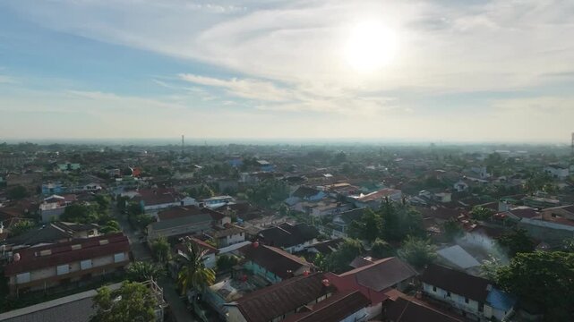 Cinematic aerial view of a small town in Indonesia, featuring residential neighborhoods, local roads, tropical greenery, and a peaceful community atmosphere.