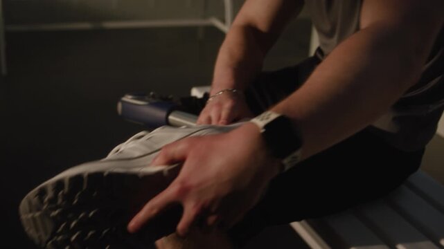 Close Up of Young Man Hands Tying Shoelaces on White Sneaker Worn on Bionic Leg Prosthesis. Powerful Visual of Inclusivity and Preparation for Fitness Journey. Adaptive Technology in Action. Handheld.