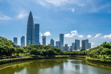 Fototapeta premium Modern urban view of Shenzhen business district with lake reflection, green trees and high-rise office buildings