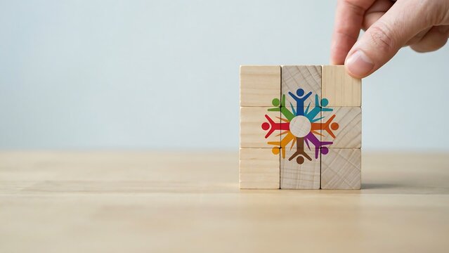 A hand places a wooden block with a colorful unity symbol on a table