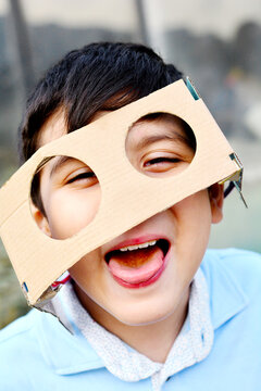 Latin kid wearing huge cardboard glasses.
