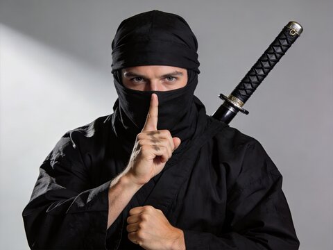Portrait of a ninja warrior holding a katana sword and making a silence gesture, symbolizing stealth, secrecy, and martial arts discipline