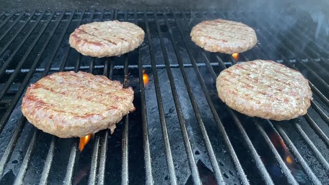 Burger-Patties auf dem BBQ-Grill &uuml;ber offener Flamme. Authentisches Food-Motiv f&uuml;r Grillen, Barbecue, Sommer, Burger, R&ouml;staromen und Outdoor Cooking.