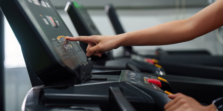Cropped hand pressing button on treadmill console for fitness workout