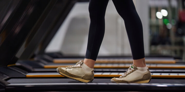 Cropped legs of woman walking on treadmill in gym for cardio workout
