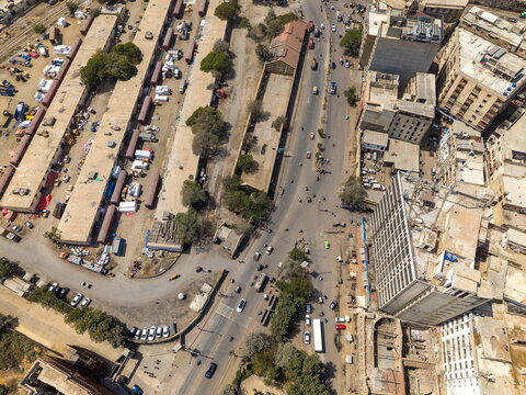 Aerial view of I.I Chundriger Rd featuring dense urban architecture, busy traffic on the main road, and adjacent industrial facilities with parked vehicles. Karachi, Sindh, Pakistan.