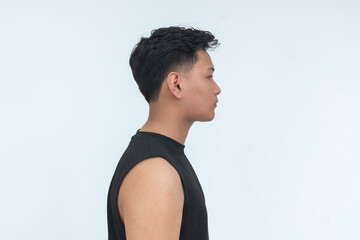 Chest-up side profile portrait of a serious young Filipino man in black sleeveless clothing, isolated on a white background. © Mdv Edwards