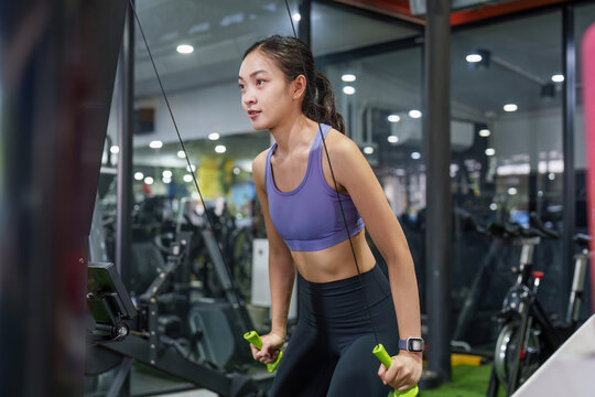 Asian woman doing cable pulldown exercise at gym for upper body strength