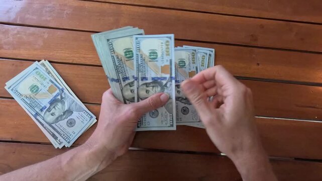 Woman hands counting stack of 100 dollar bills put in stack on table, leafing through banknotes. Close-up. Concept of making money. Accumulated capital. Financial planning, savings. 