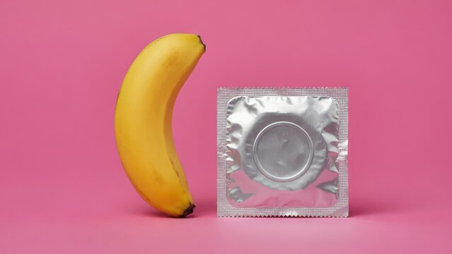 Condom and Banana On Pink Background Symbolizing Safe Sex, Contraception and Sexual Health Education