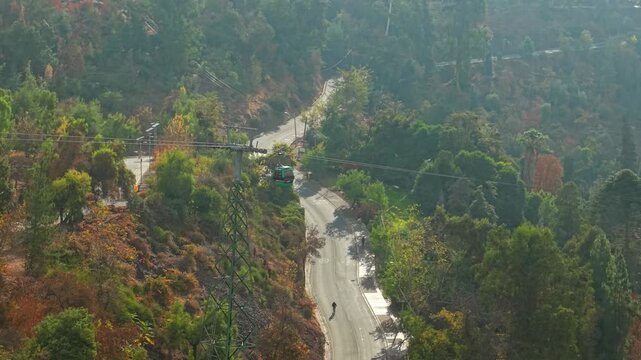 Aerial orbit establishing the Santiago cable car, with people exercising and riding bicycles down San Cristobal Hill, Santiago, Chile