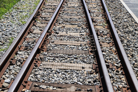 Close-up top view of parallel railway tracks with wooden sleepers and gravel ballast