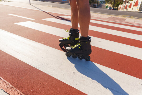 Man's legs in rollerblades standing on a pedestrian crossing on a sunny day