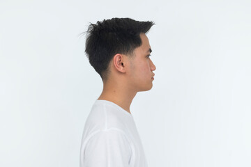 A young Southeast Asian man in a side-view studio portrait with a serious expression, wearing a white shirt against a clean background. © Mdv Edwards