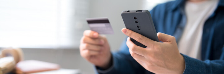Young adult using smartphone and credit card for secure online payment and mobile banking transaction at home © Audtakorn