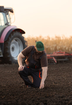 Farmer Inspecting Soil Quality in Agricultural Field Near Tractor
