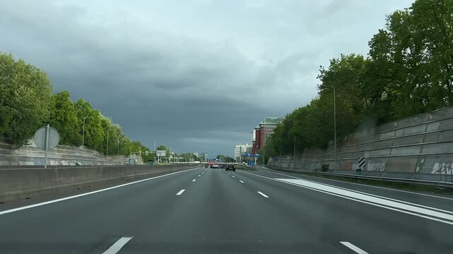 Amsterdam Netherlands highway, Urban motorway with moving traffic beside green city buildings