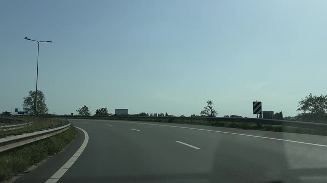 Amsterdam Netherlands highway, Curving empty highway through a green landscape under a clear sky