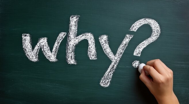 Hand writing why? in white chalk on a dark green chalkboard